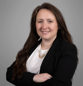 Erin Woodrum, Family Law Attorney at Brazil Family Law, smiling confidently with arms crossed against a gray backdrop.
