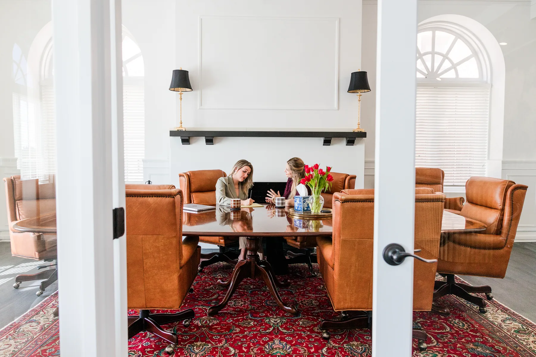 Two attorneys meeting at the conference table at Brazil Family Law in Winston-Salem, seen through the glass doors (staged photo)